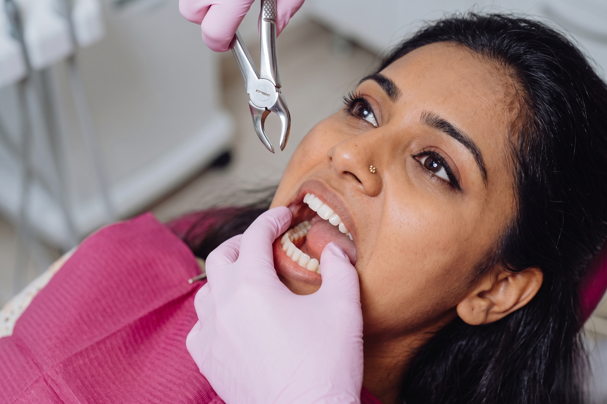 Dentist performing a dental procedure on a patient with tools, X-ray visible on monitor in modern dental clinic